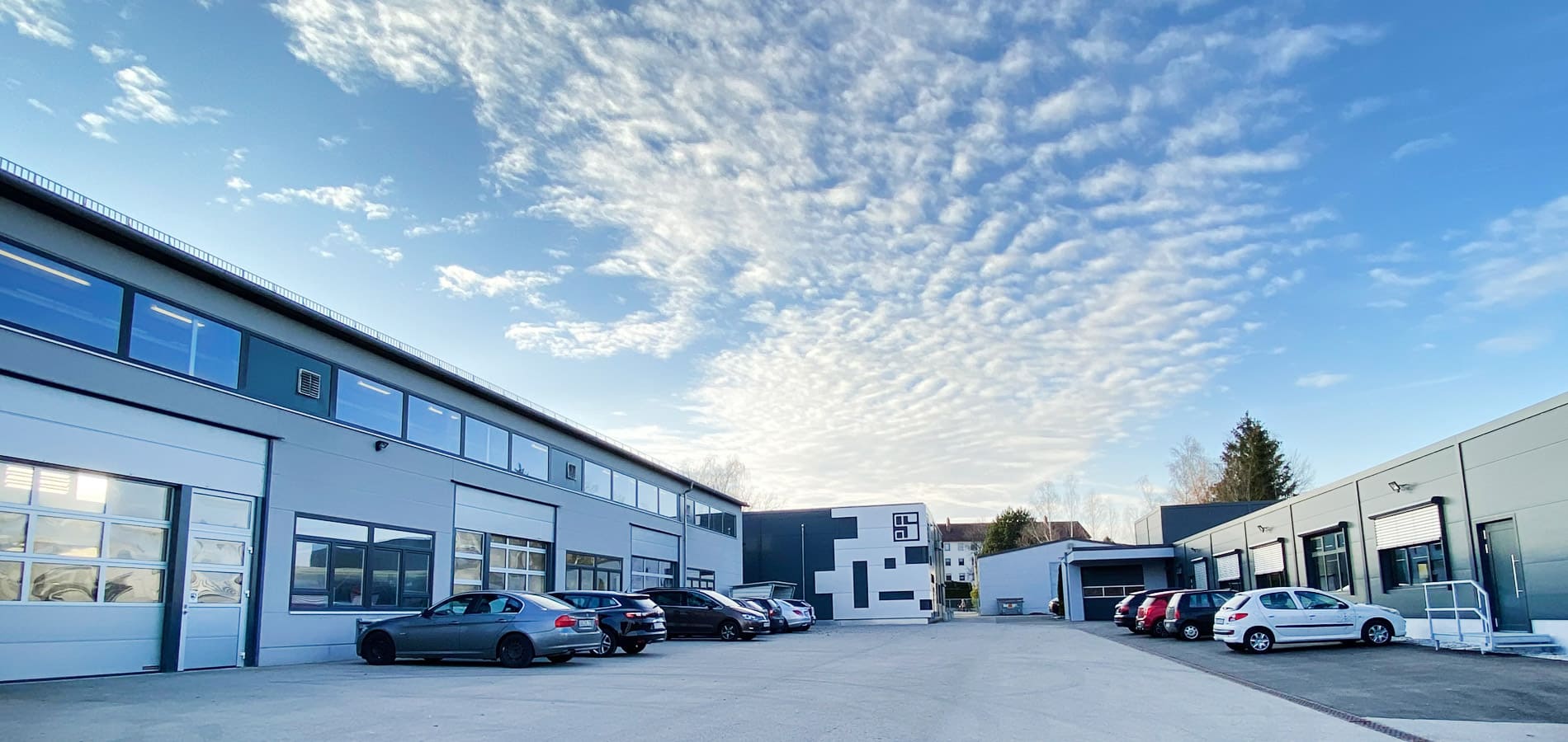 Ein großes Industriegebäude mit parkenden Autos davor.